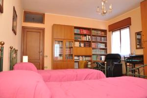 um quarto com camas cor-de-rosa e estantes de livros em Giangurgolo B&B em Rende