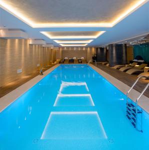 a swimming pool with blue water in a hotel room at Kronwell Brasov Hotel in Braşov