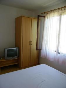 a bedroom with a bed and a tv and a window at Apartments Fran-30m from sea in Vinišće