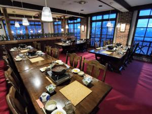 a dining room with tables and chairs and windows at Fujio Pension Madarao Apartment Hotel & Restaurant in Iiyama