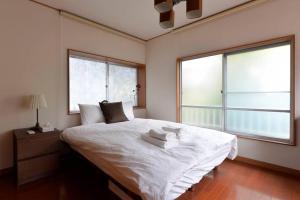a bedroom with a white bed with two windows at Annex Shibuya in Tokyo