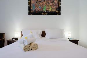 a bedroom with a white bed with towels on it at WIRA Homestay & Spa in Uluwatu