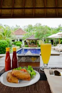 a table with a plate of food and a glass of juice at WIRA Homestay & Spa in Uluwatu