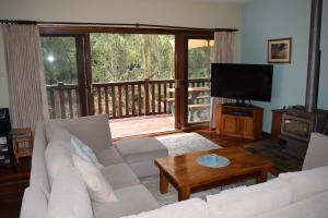 a living room with a couch and a flat screen tv at Bluebell Cottage in Leura