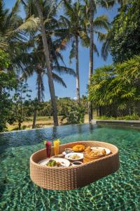 una bandeja de comida en una mesa en medio de una piscina en Villa Kayu Lama en Ubud
