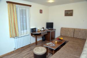 ein Wohnzimmer mit einem Sofa und einem Schreibtisch mit einem Computer in der Unterkunft Alva Hotel & Spa in Zaghkadsor