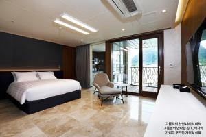 a bedroom with a bed and a chair and a balcony at Pine Forest Jeongseon Alpine Resort in Jeongseon