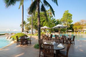 港生Novotel Rayong Rim Pae Resort的游泳池旁的餐厅配有桌椅