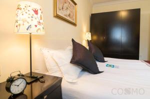 a bedroom with a bed with a clock and a lamp at Ladoll Service Apartments in Shanghai