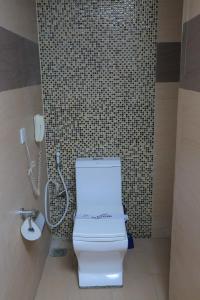 La salle de bains est pourvue de toilettes blanches et d'un téléphone. dans l'établissement Tiffany Diamond Hotels Ltd - Indira Gandhi street, à Dar es Salaam