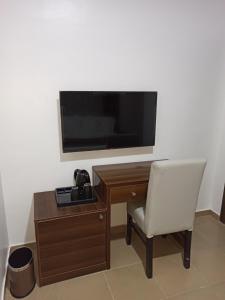 a desk with a chair and a television on a wall at Presken Residence Annex in Ikeja