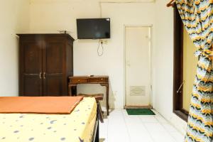 een slaapkamer met een bed en een tv aan de muur bij Kos VIP Josh in Yogyakarta