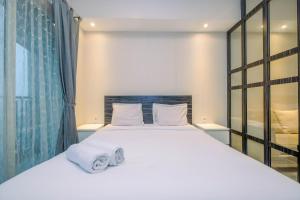 a bedroom with a large white bed with towels on it at Warm and Cozy Studio at The Oasis Cikarang Apartment By Travelio in Cikarang