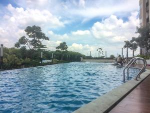 a swimming pool at a resort with blue water at Warm and Cozy Studio at The Oasis Cikarang Apartment By Travelio in Cikarang