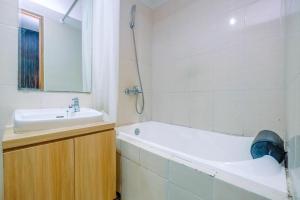 a bathroom with a tub and a sink and a bath tub at Warm and Cozy Studio at The Oasis Cikarang Apartment By Travelio in Cikarang +6 photos