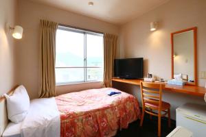 熊野市にあるビジネスホテル みはらし亭のベッド、デスク、窓が備わるホテルルームです。