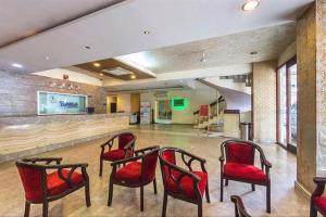 a waiting room with red chairs and a bar at Hotel Jaya International in Hyderabad