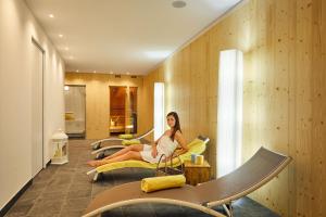 a woman sitting on a couch in a hotel room at Alpin Relais B&B Villa Melisse in Colfosco