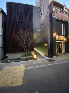 a street with two buildings and a tree in the middle at GRAND BASE Nagasaki in Nagasaki