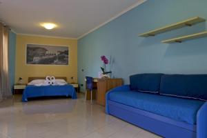 un soggiorno con divano blu e letto di Hotel Ristorante Al Canto delle Sirene a Terracina