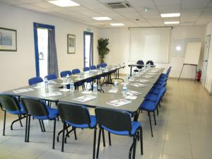 une salle de conférence avec de longues tables et des chaises bleues dans l'établissement Euro Hôtel Airport Orly Rungis, à Fresnes