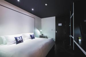 a bedroom with a large white bed with black walls at Blu Monkey Hub and Hotel Phuket Town- Free All Day Coworking space in Phuket Town