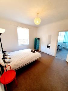 a bedroom with a large bed and a red chair at Three Bedroom Apartment In Heart Of Rayleigh in Rayleigh