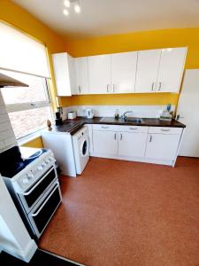 uma cozinha com armários brancos, um lavatório e um fogão em Three Bedroom Apartment In Heart Of Rayleigh em Rayleigh