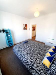 a bedroom with a large bed with blue and yellow pillows at Three Bedroom Apartment In Heart Of Rayleigh in Rayleigh