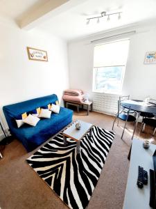 uma sala de estar com um sofá azul e um tapete de zebra em Three Bedroom Apartment In Heart Of Rayleigh em Rayleigh