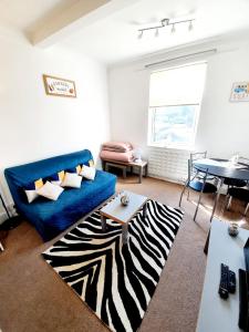 a living room with a blue couch and a zebra rug at Three Bedroom Apartment In Heart Of Rayleigh in Rayleigh