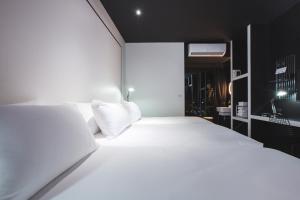 a white bed with white pillows in a room at Blu Monkey Hub and Hotel Phuket Town- Free All Day Coworking space in Phuket Town