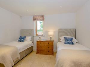 a bedroom with two beds and a dresser and a window at Mulberry Barn Annx - Self Contained Near Winchester in Micheldever