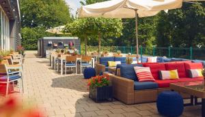 un patio con sofá, mesas y sillas en WestCord Hotel Delft, en Delft