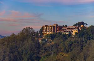 a building on top of a hill with trees at Club Himalaya, by ACE Hotels in Nagarkot