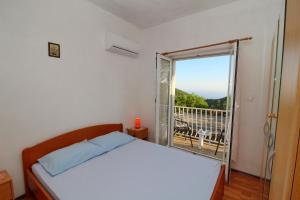 a bedroom with a bed and a window with a balcony at Apartments Felix in Babino Polje
