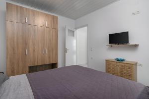1 dormitorio con 1 cama, armarios de madera y TV en wood and stone en Adamas