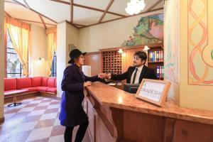 a man and a woman shaking hands at a counter at Palace Pontedilegno Resort in Ponte di Legno