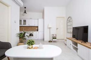- un salon blanc avec une table blanche et une télévision dans l'établissement Domus Lux Houses by Konnect, à Corfou