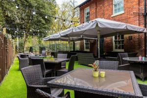 un patio con tavoli, sedie e ombrellone di Hand and Spear a Weybridge