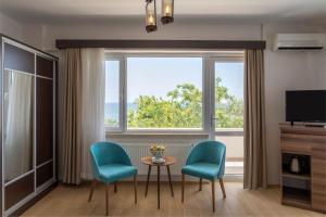 ein Wohnzimmer mit einem Tisch, zwei Stühlen und einem Fenster in der Unterkunft Troas Beach Hotel in Tavaklı