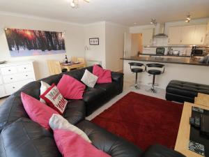 un soggiorno con divano in pelle nera e cuscini rosa di Cumbria Court a Windermere