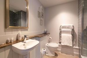 bagno con lavandino, servizi igienici e specchio di Crown Hotel a Chertsey