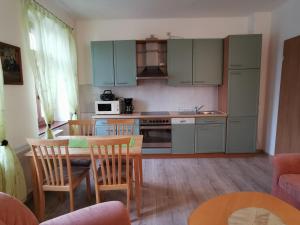 eine Küche mit einem Tisch und Stühlen sowie eine Küche mit blauen Schränken in der Unterkunft Ferienwohnung "Zur Kleinbahn" in Zittau
