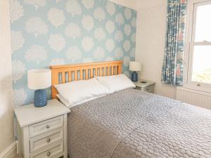 a bedroom with a bed with a blue wall at 3 Top View Cottages in Salcombe