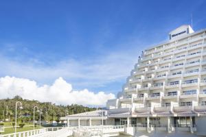 a large white hotel with a blue sky in the background at Sheraton Okinawa Sunmarina Resort in Onna