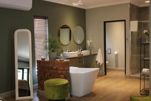 a bathroom with a tub and a sink and mirror at Pepper Tree Venue & Guesthouse in Bloemfontein