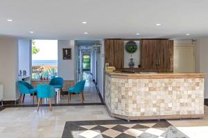 a kitchen with a counter and blue chairs at Troas Beach Hotel in Tavaklı