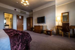 a hotel room with a bed and a flat screen tv at Bridge Hotel in Greenford