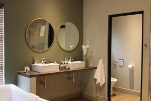 a bathroom with two sinks and two mirrors on the wall at Pepper Tree Venue & Guesthouse in Bloemfontein